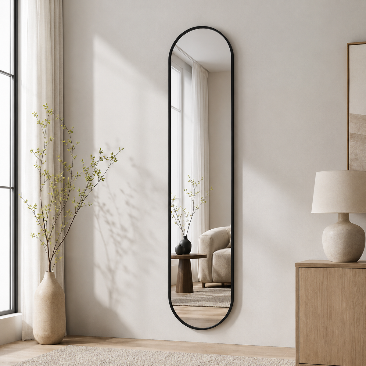 Ovalt helfigur spejl med sort ramme 26x160 cm på væg ved kommode med lampe